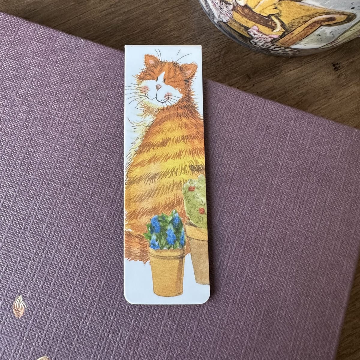 Alex Clark Cat & Pot magnetic bookmark displayed on a closed journal, highlighting the compact magnetic design and charming garden-inspired cat artwork.