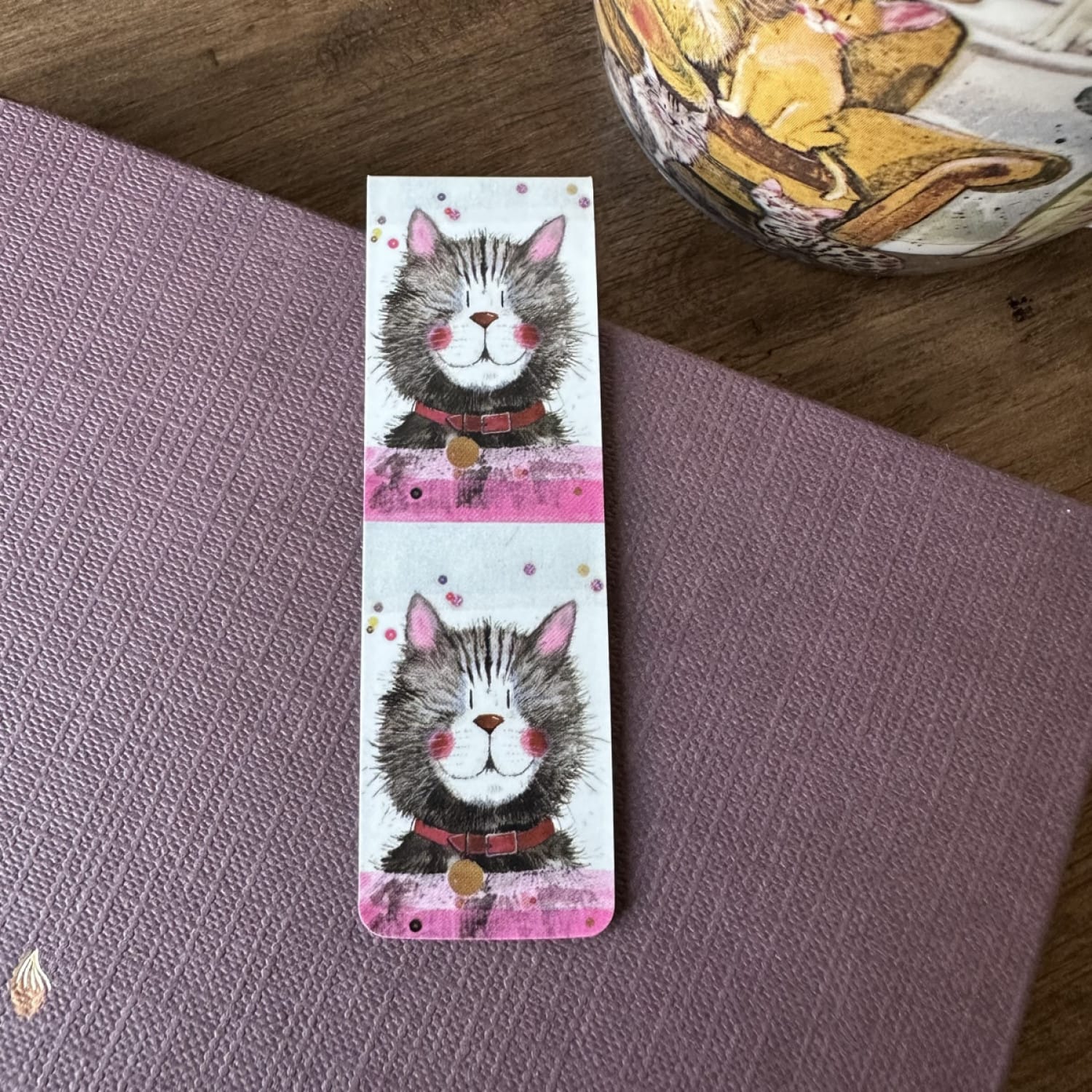 Alex Clark Klaus magnetic cat bookmark displayed on a closed journal, highlighting the compact magnetic design and charming cat artwork.