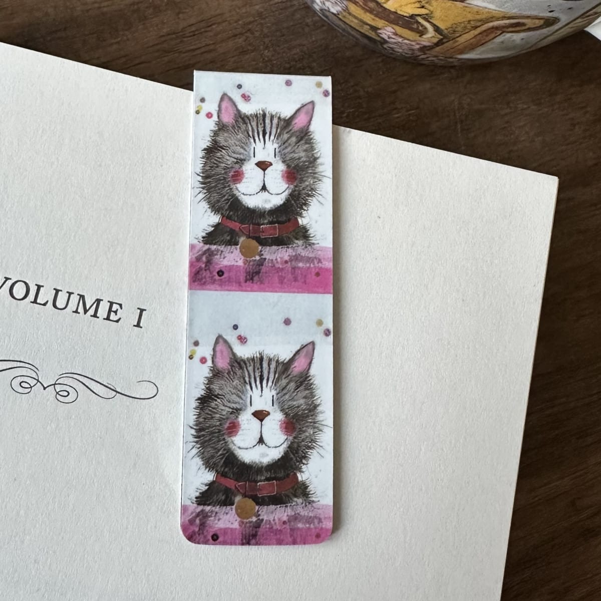 Alex Clark Klaus magnetic cat bookmark clipped onto the page of an open book, showing how the magnetic bookmark securely holds its place.