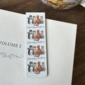 Alex Clark Marvellous Moggies magnetic bookmark clipped onto the page of an open book, showing how the magnetic bookmark securely holds its place.
