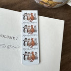 Alex Clark Marvellous Moggies magnetic bookmark clipped onto the page of an open book, showing how the magnetic bookmark securely holds its place.
