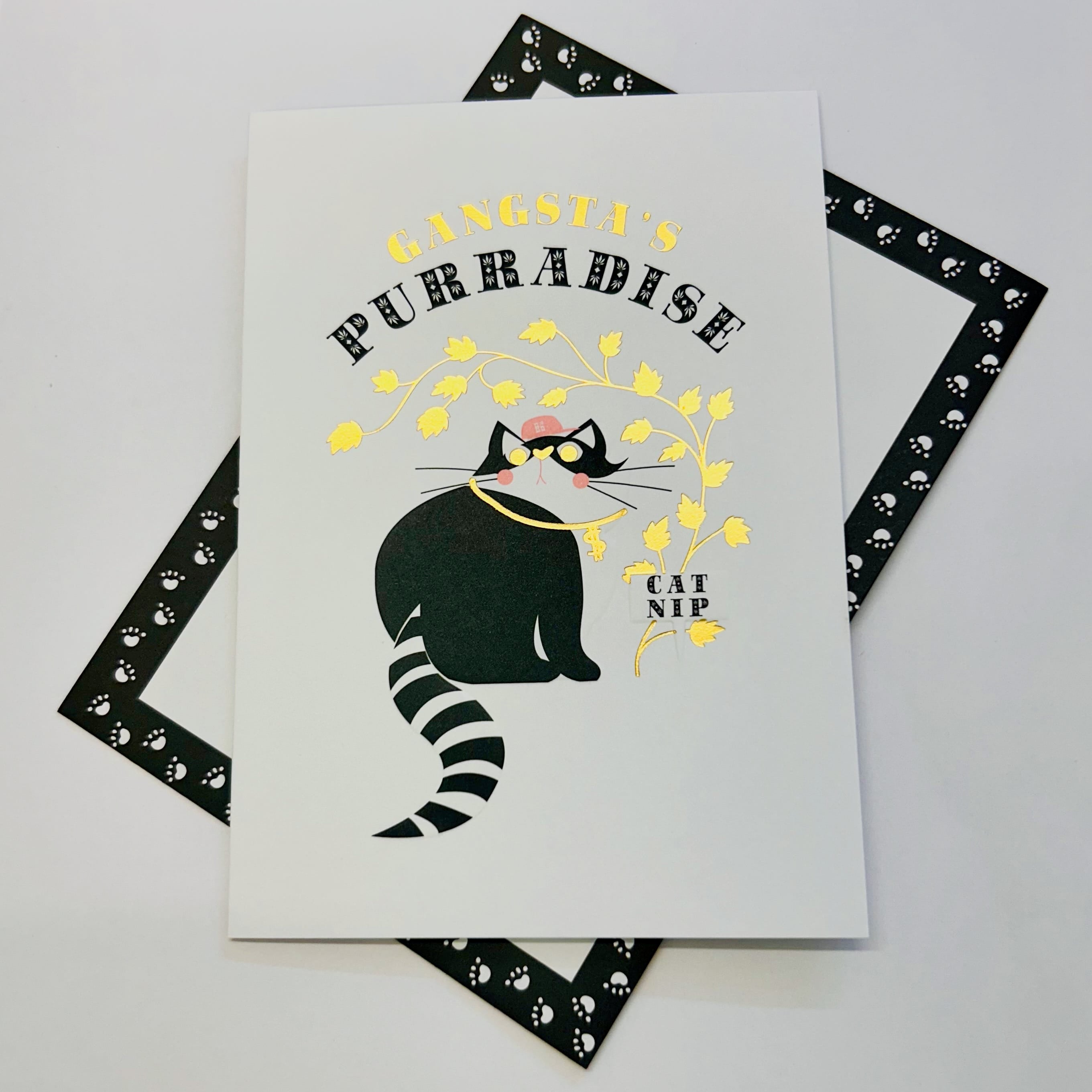 Art File Gangsta's Purradise cat greetings card featuring a cool black cat wearing a cap and gold chain with catnip leaves, gold-coloured accents and embossed details.