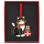 Boxed black and white tuxedo cat Christmas hanging decoration wearing a striped scarf beside wrapped presents