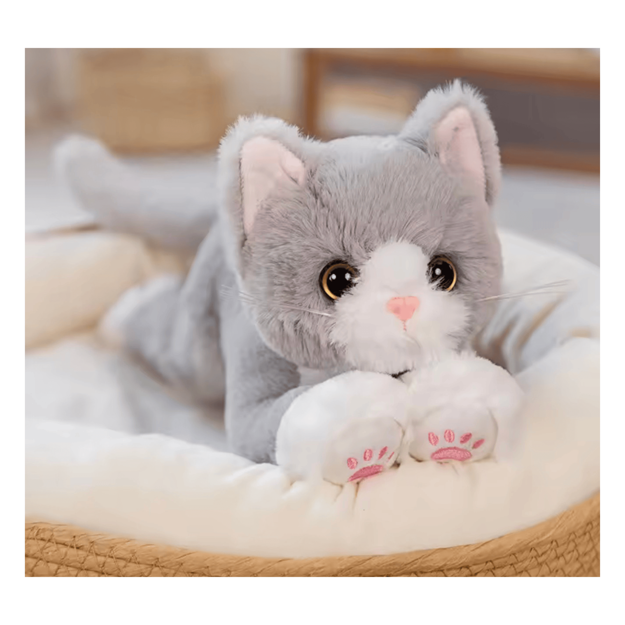 Large grey and white fluffy cat teddy toy with oversized sparkling eyes, pink paw pads and soft plush fur lying on a cosy cushion, measuring 53cm.
