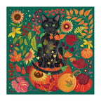 Completed Galison Whiskers of Autumn 500 piece foil jigsaw puzzle showing a green-eyed black cat sitting among orange pumpkins, sunflowers and autumn foliage.