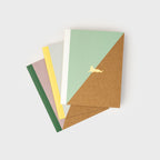 Three A5 kraft paper notebooks with geometric colour blocks and a golden cat icon on the covers.
