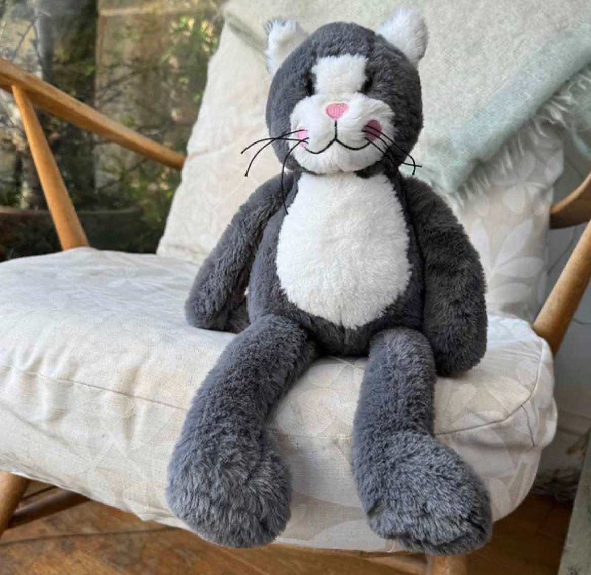 Plush toy cat sitting on a cushioned chair