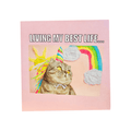 Living My Best Life funny cat greetings card featuring a tabby cat wearing a colourful party hat with rainbow artwork on a pink background