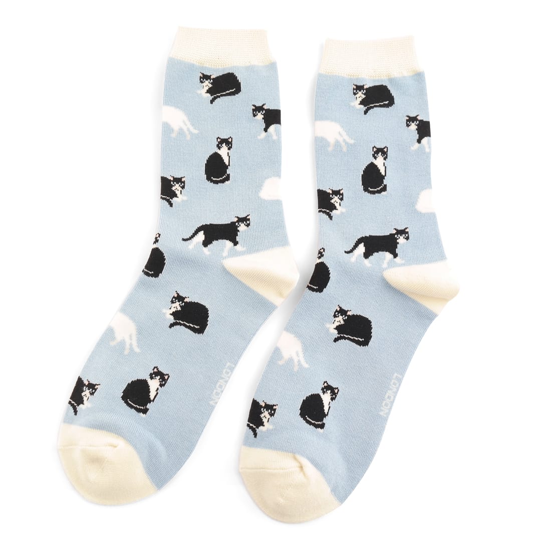Pair of Miss Sparrow Ladies Bamboo Socks in powder blue featuring playful black and white cat silhouettes on a soft blue background with cream heels, toes and cuffs, made from a soft bamboo-rich fabric.