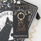 The Protector Magick Black Cat Keyring with celestial moon and star design displayed beside a mystical black cat Book of Spells