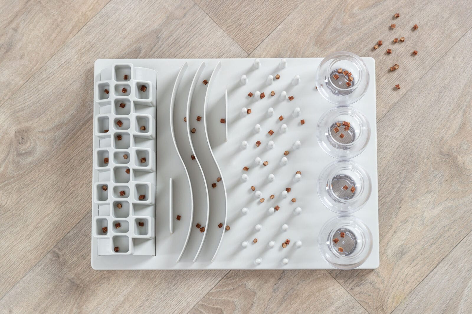 Overhead view of the Trixie Fun Board cat enrichment game showing five different puzzle challenges for treats and dry food